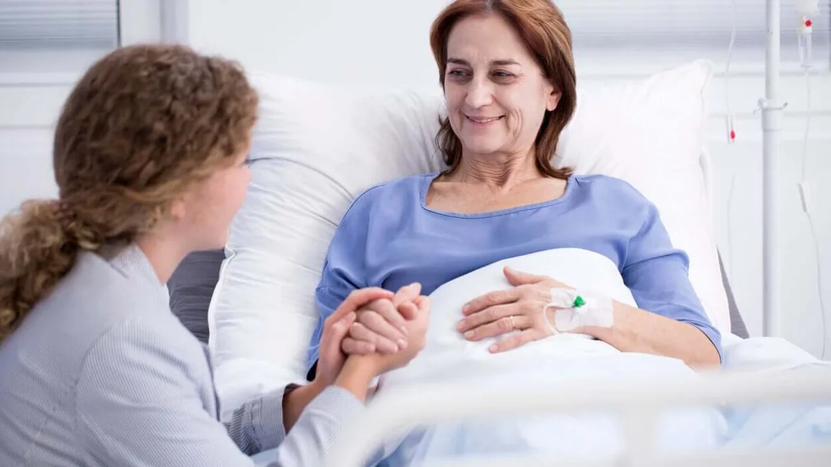 Une soignante tient la main d&rsquo;une patiente en soins palliatifs