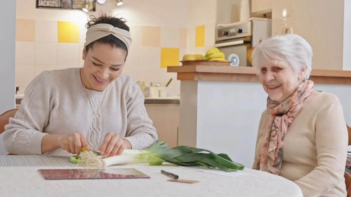 Une auxiliaire de vie aide une femme âgée en cuisine