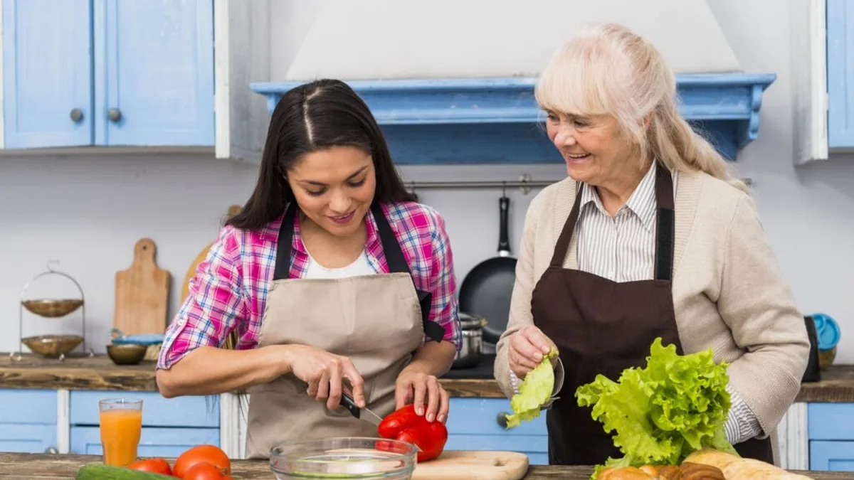 Une intervenante prépare le repas avec une senior