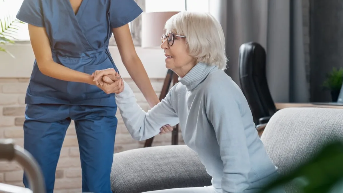 Une aide à domicile aide une personne âgée à se relever