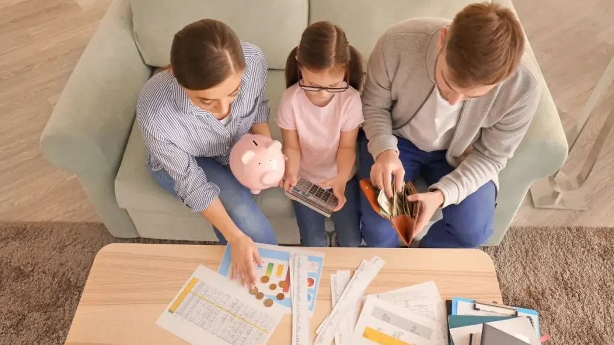 Une famille autour d&rsquo;une table vérifie son budget sur une calculatrice