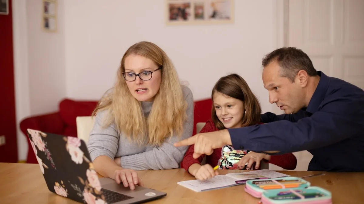Parents aidant leur enfant à remplir une démarche sur un ordinateur