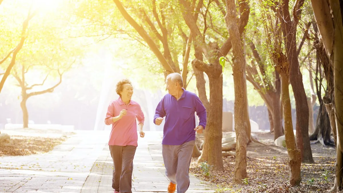Un couple de seniors marche dans un parc le matin