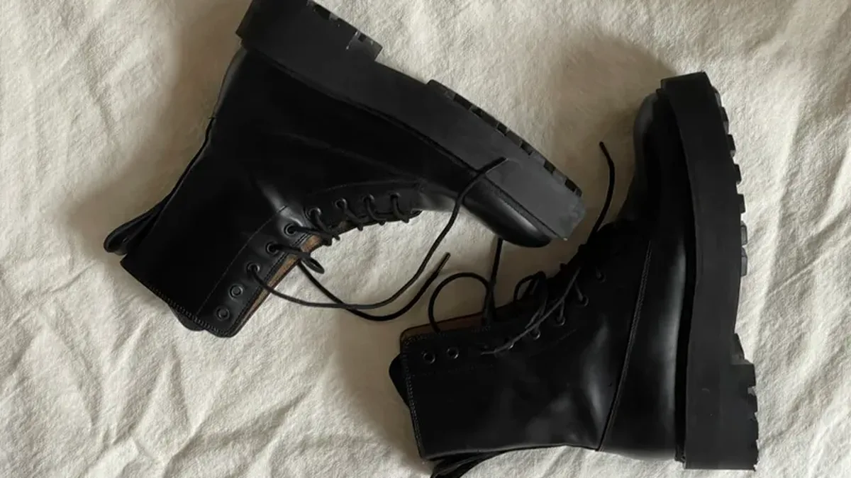 Paire de bottes noires à semelles épaisses, posée sur un tissu blanc