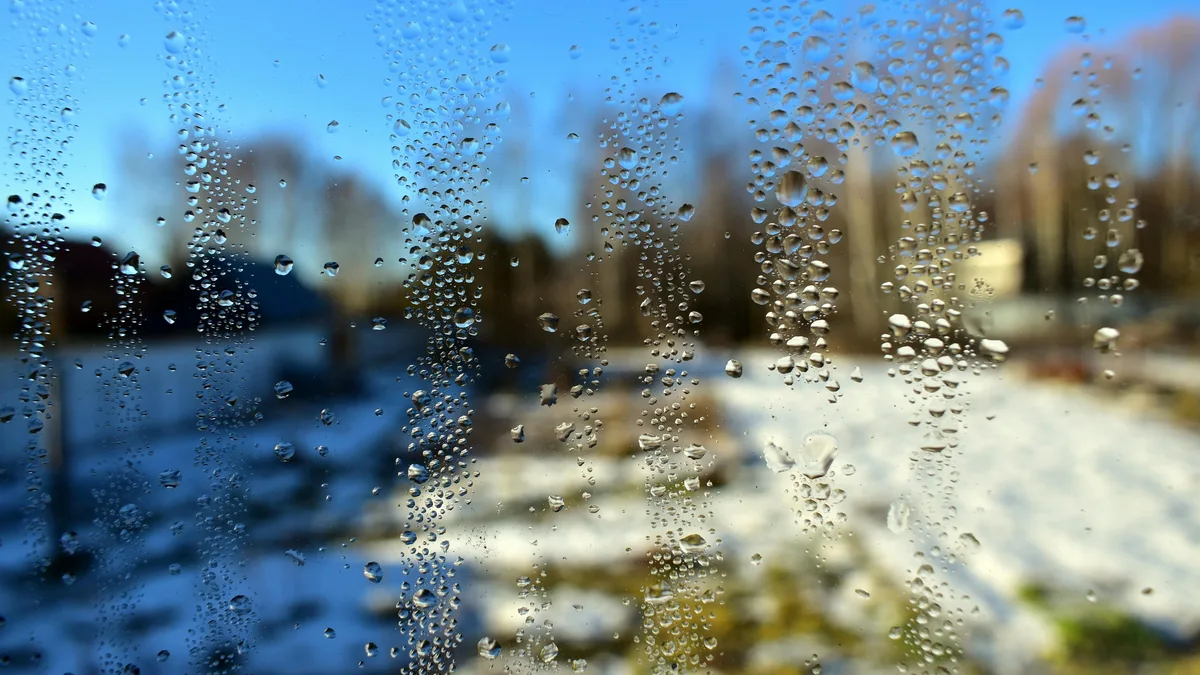 Gros plan sur des gouttes de condensation qui ruissellent sur une vitre