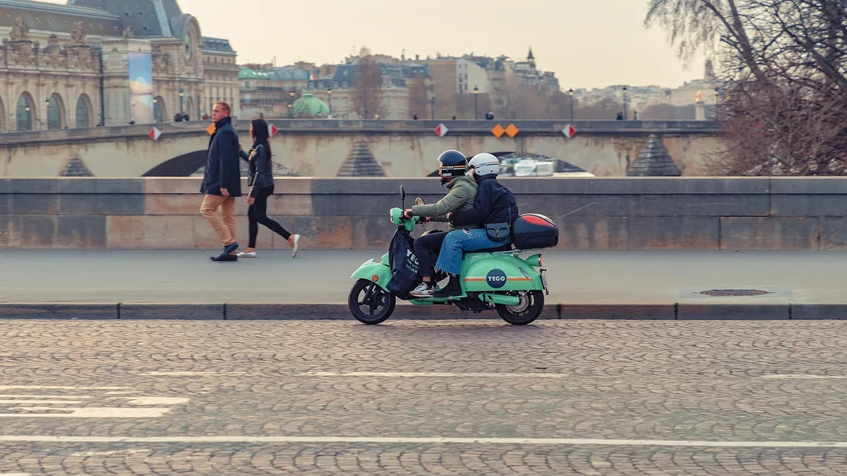 Deux personnes sur un scooter dans une rue de Paris