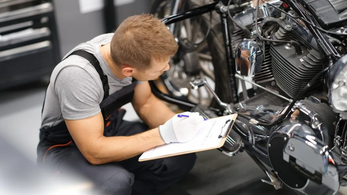 Un mécanicien inspecte le moteur d&rsquo;une moto dans un atelier
