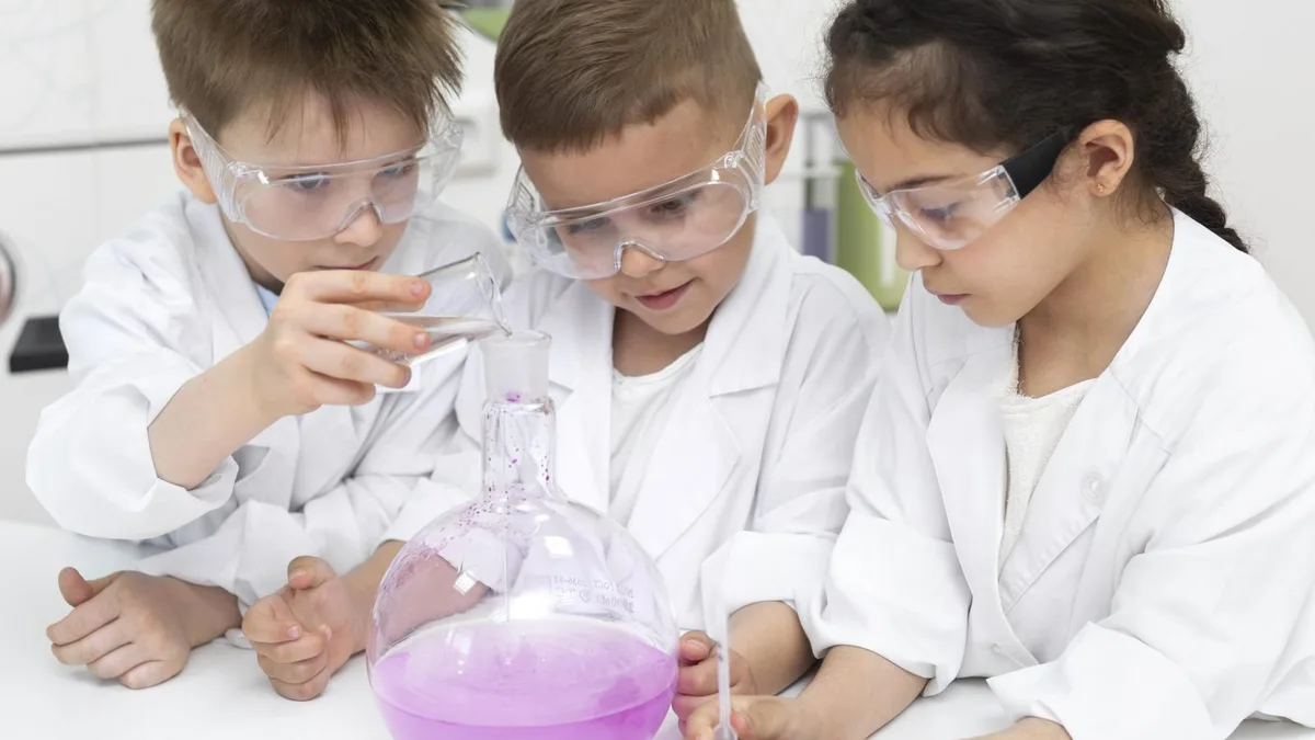 Des enfants en blouse blanche réalisent une expérience de chimie