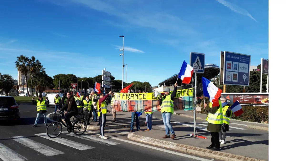 Des gilets jaunes occupent un rond-point, drapeaux français en main