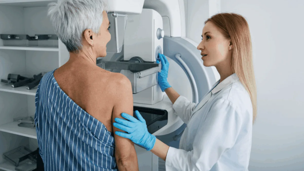 Une femme d&rsquo;une cinquantaine d&rsquo;années accompagnée d&rsquo;une radiologue devant l&rsquo;appareil de mammographie
