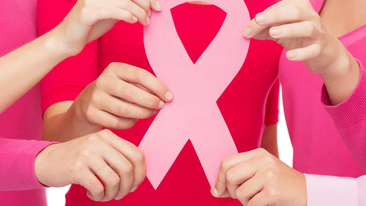 Des femmes tenant un grand ruban rose, symbole de la lutte contre le cancer du sein