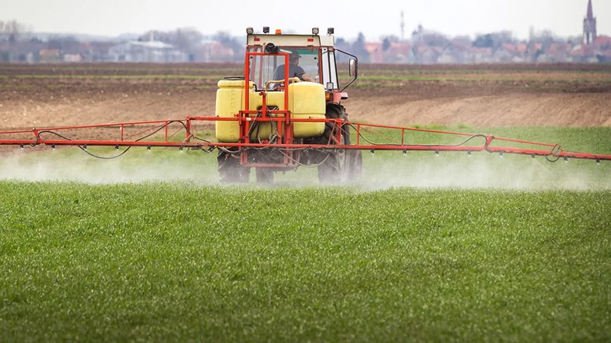 Tracteur procédant à l&rsquo;épandage de pesticides dans un champ