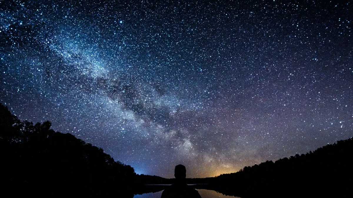 Une personne observe le ciel étoilé, allongée dans l&rsquo;herbe