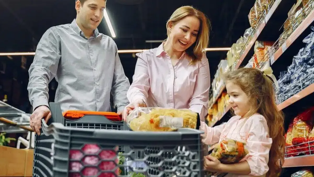 Une famille fait ses courses au supermarché avec un caddie rempli