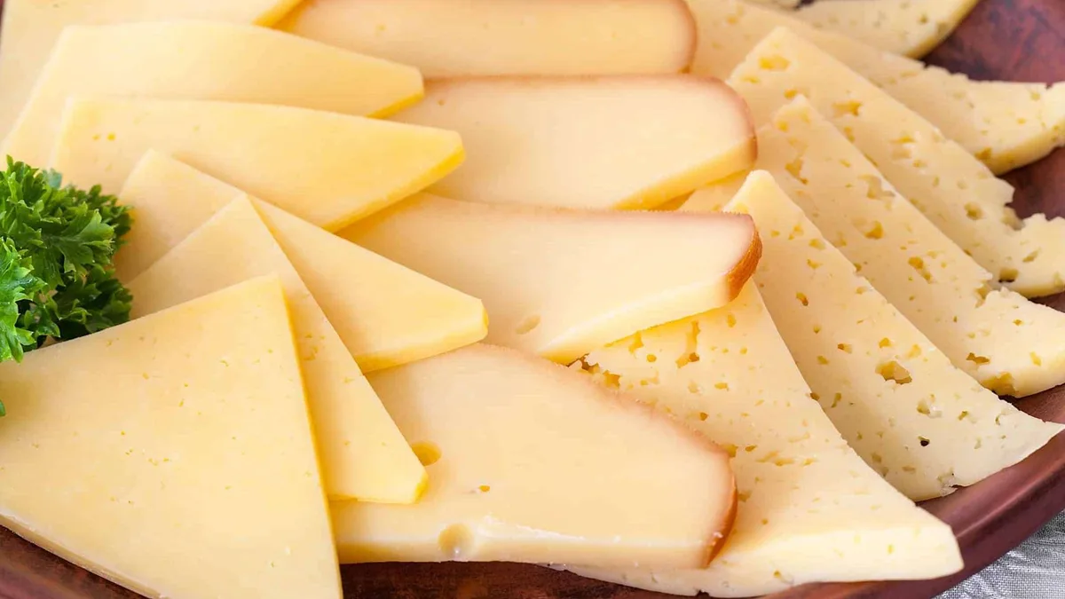 Tranches de fromage à raclette disposées sur un plateau en bois