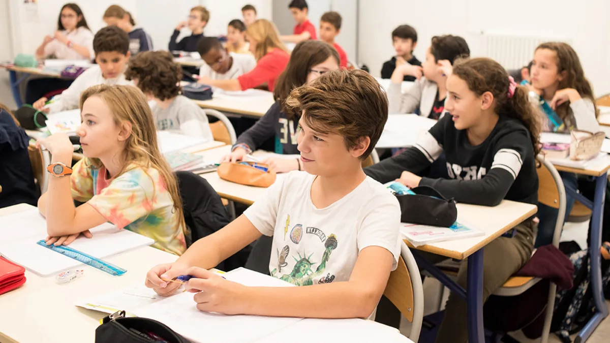 Une classe de collège pendant un cours, les élèves assis face au tableau