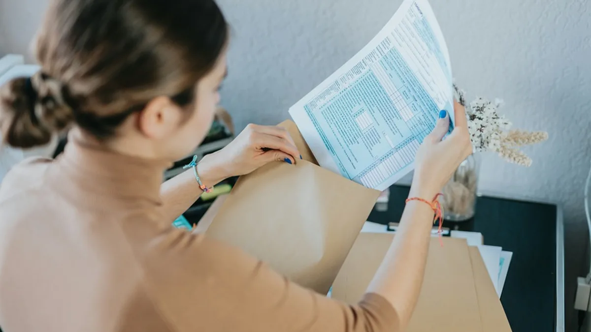 Une contribuable sort son avis d&rsquo;imposition de son enveloppe avant de régler en ligne
