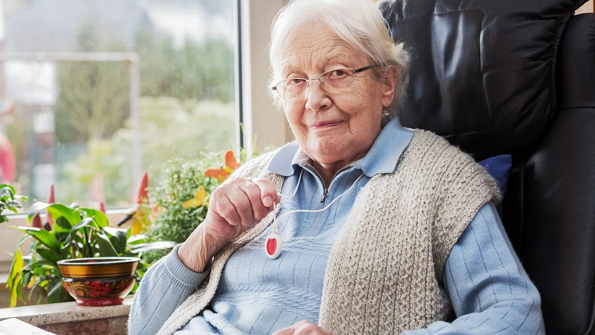 Une senior souriante portant son bouton d&rsquo;alerte